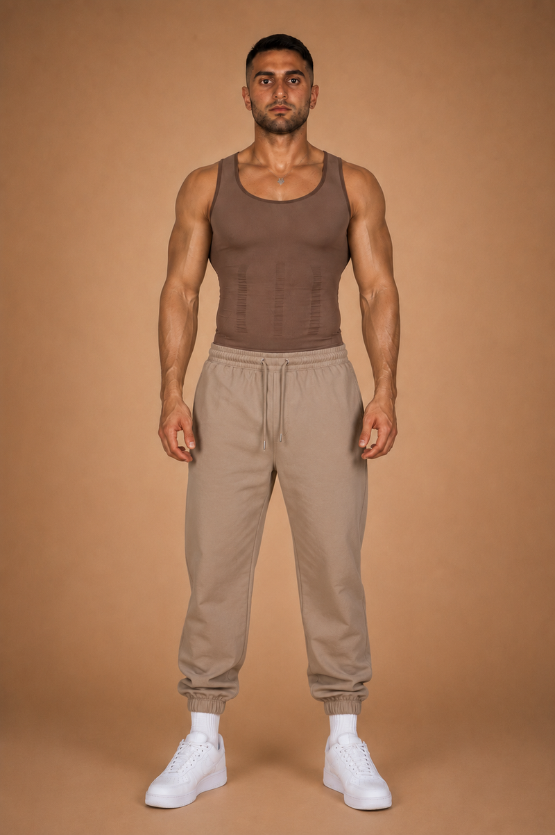 the cinch — brown seamless compression tank worn with sand joggers, full-length front view against warm backdrop