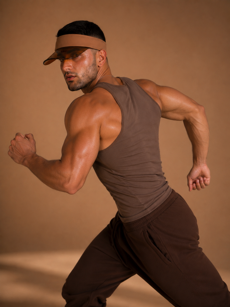 the shade — tan visor with amber lens worn with the cinch tank, portrait against warm backdrop