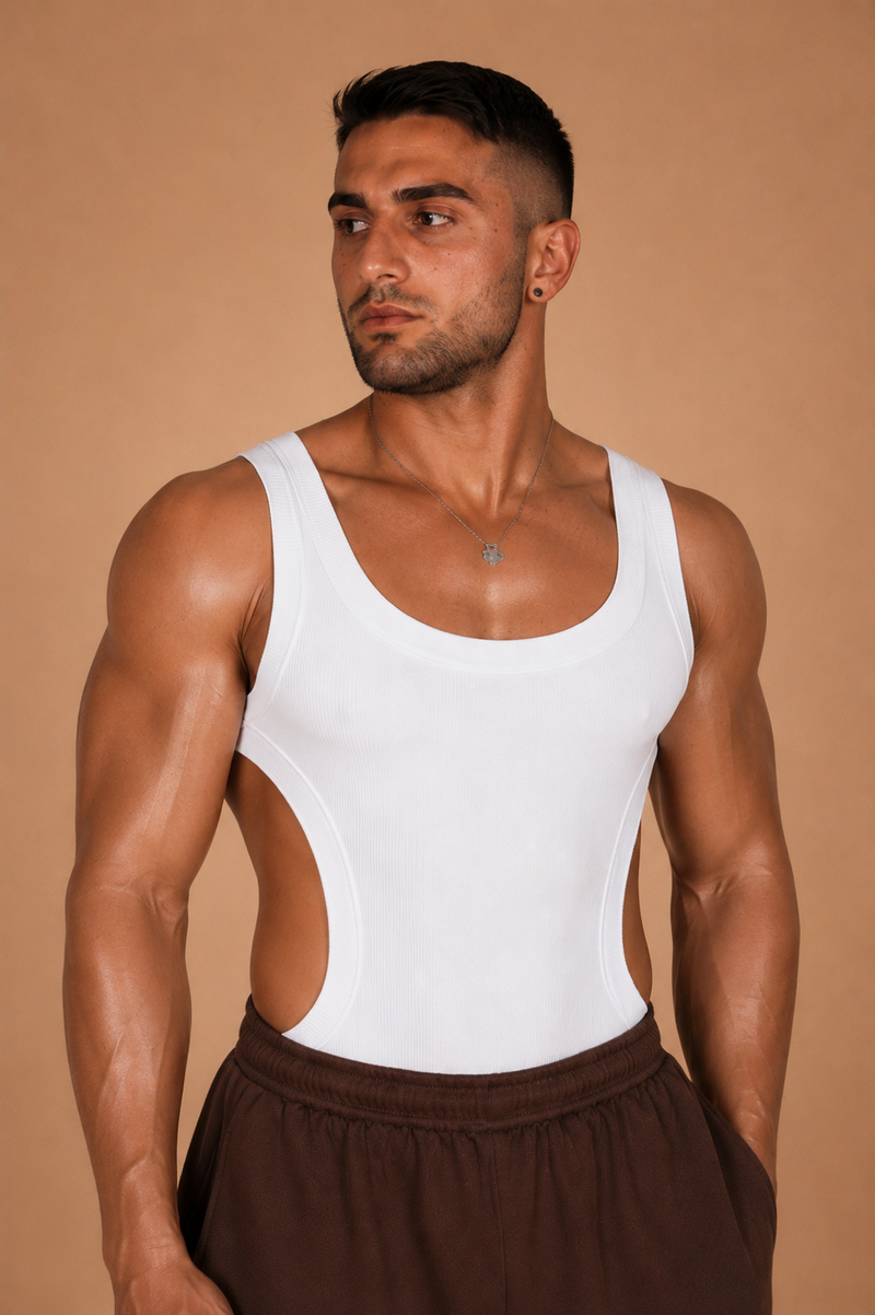 the cutaway — white rib-knit tank with deep side cutouts, front view with brown track pants against warm backdrop